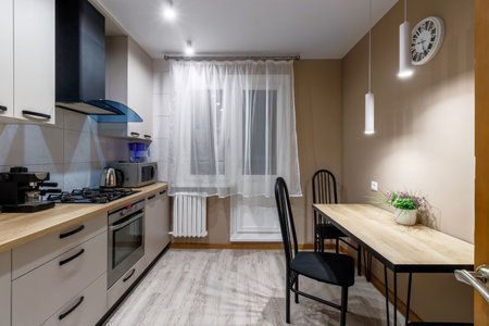 View of a modern kitchen with blue hood, kitchen appliances and dining table.の写真素材
