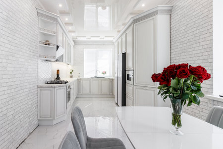 Modern interior with white kitchen and kitchen appliances in the country house with a bouquet of roses in the foreground.の写真素材