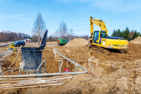 Excavator dig the trenches at a construction site. Trench for laying external sewer pipes. Sewage drainage system for a multi-story building. Digging the pit foundation.の写真素材