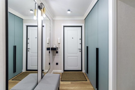 White entrance door in a modern renovated hallway with large mirrors and wardrobe.の写真素材