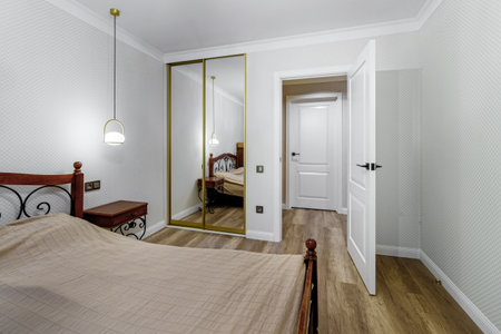 View of the door and wardrobe with a huge mirror in a modern bedroom.の写真素材