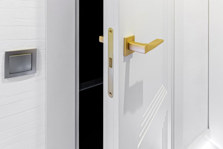 Classic style white door. Opened white door to the bathroom. Classic white door with golden handle. close-up.の写真素材