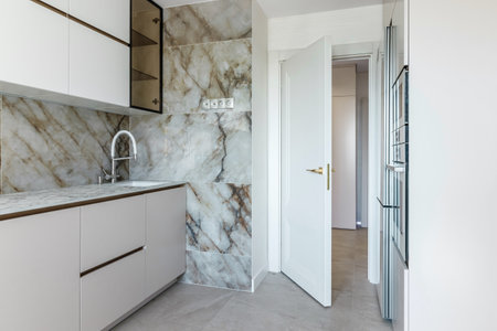 Modern kitchen with sink and faucet white door exit from kitchen.の写真素材