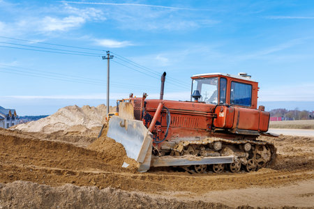 An old orange bulldozer performs work to level the sandy soil.の写真素材
