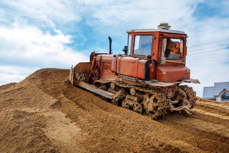 An old orange bulldozer performs work to level the sandy soil.の写真素材