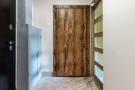 Entrance wooden door of natural color, in a multi-storey building. Entrance to the apartment.の写真素材