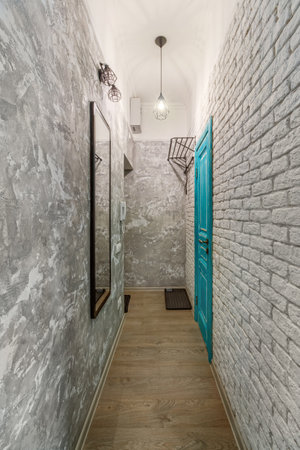 Turquoise door in the hallway, with a large mirror and brick walls.の写真素材