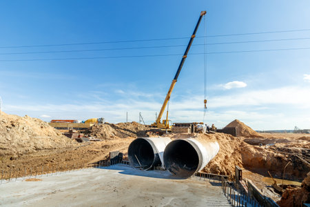 Connecting a trench drain to a concrete manhole structure at construction site. Concrete pile in formwork frame for construct stormwater and underground utilities, pump stations, sewers pipes.の写真素材