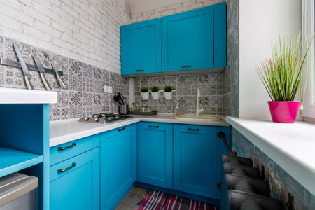 Very small kitchen with blue cabinets and window.の写真素材