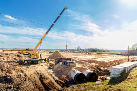 Connecting a trench drain to a concrete manhole structure at construction site. Concrete pile in...