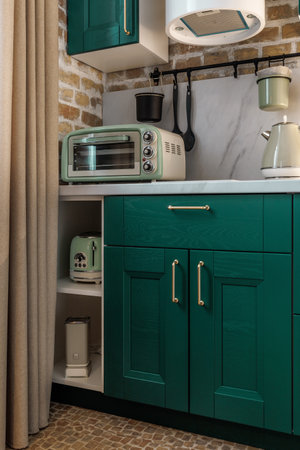 Modern retro-style kitchen with green cabinets and brick wallsの写真素材