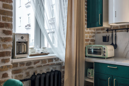 Modern retro-style kitchen with green cabinets and brick walls.の写真素材