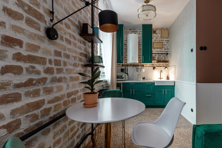 Modern retro-style kitchen with green cabinets and brick walls.