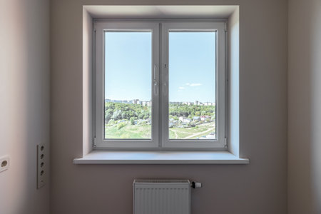 The window in the apartment overlooks the green forest and the blue sky.の写真素材