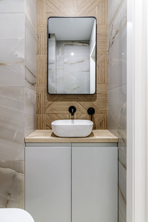Modern bathroom with black fixtures, mirror and white sink.の写真素材
