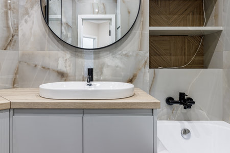 Modern bathroom with black fixtures, mirror and white sink.の写真素材