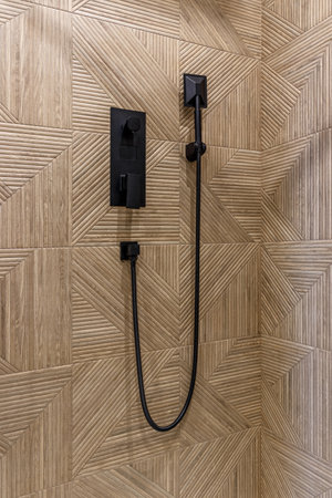 Close up of the shower area. On the wall is a black faucet with a large shower headの写真素材