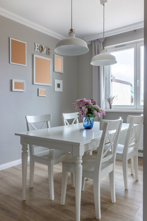 Large dining table in a modern house, with white chairs and a beautiful bouquet of lilacs in a blue vase.の写真素材