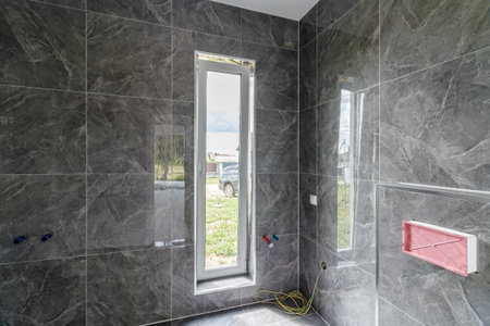 Bathroom with tiled walls before installing shower and sink, is in the apartment that is under construction, remodeling, renovation, overhaul, extension, restoration and reconstruction. Concept of homeの写真素材