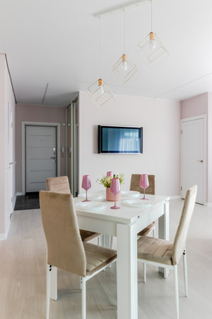 A modern living room combined with a kitchen, in light colors. Dining table with pink tableware.の写真素材