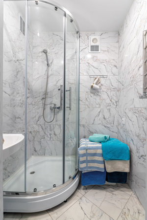 A simple bathroom with a silver shower, a square mirror and classic white tiles.の写真素材