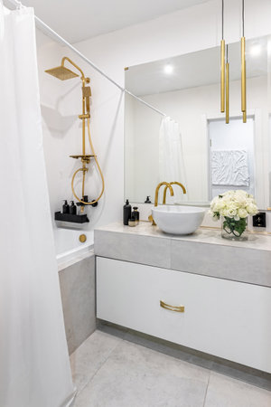 A modern bathroom in light colors with gold fixtures and a bouquet of white flowers.の写真素材