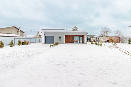 Modern one-storey house with a flat roof in winter, the plot is covered with snowの写真素材