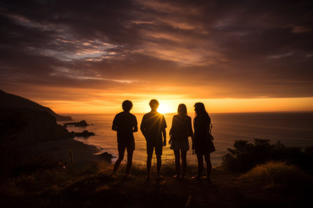 Night summer camping on lake shore. Group young happy tourists sitting in high grass around bonfire near tent under beautiful blue evening sky. Tourism, friendship and beauty of nature conceptの素材