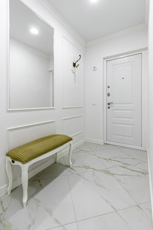White entrance hall interior with wooden banquette with gold top.の写真素材