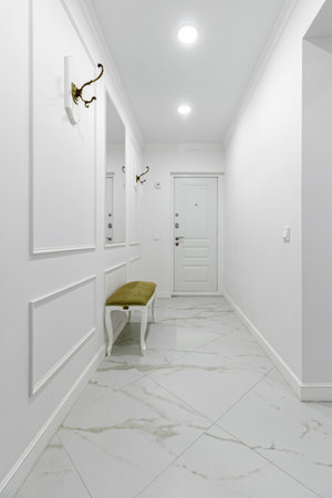 White entrance hall interior with wooden banquette with gold top.の写真素材