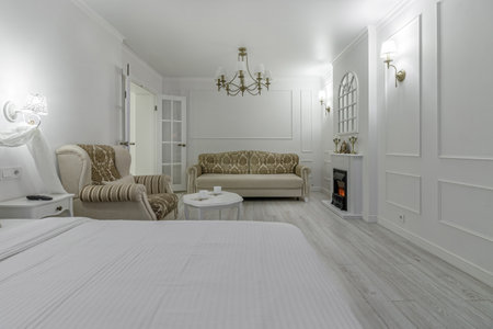 Interior in light colors with a bio fireplace, illuminated by burning sconces on the wall.の写真素材