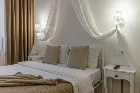 Close-up of the bed, bedside tables, glowing sconces above them.の写真素材