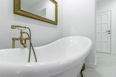 Freestanding bathtub bowl located in the hallway of the apartment, with golden legs and a large...