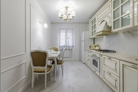 A beautiful kitchen detail with white cabinets, a gold faucet, white marble countertops, and a brown picket ceramic tile backsplash.の写真素材