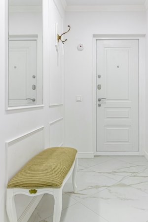 White entrance hall interior with wooden banquette with gold top.の写真素材