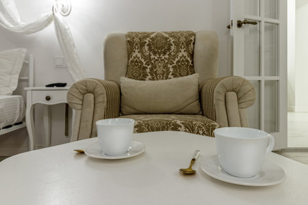 Living room interior in gold and white colors with white coffee table and coffee cups.の写真素材