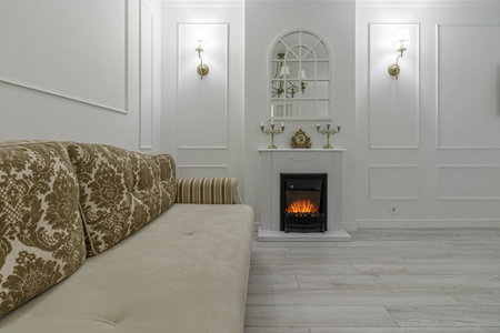 Interior in light colors with a bio fireplace, illuminated by burning sconces on the wall.の写真素材