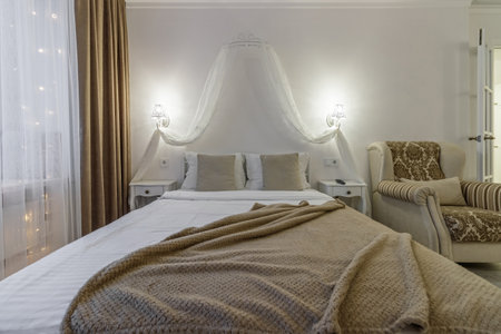 Close-up of the bed, bedside tables, glowing sconces above them.の写真素材