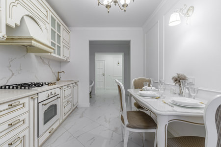 A beautiful kitchen detail with white cabinets, a gold faucet, white marble countertops, and a brown picket ceramic tile backsplash.の写真素材