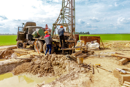 Worker drilling into the earth with his well drilling machine to extract water. Drilling equipment, drills well for water extractionの写真素材