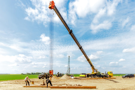 A construction site with a lifting crane and workers installing water pipesの写真素材