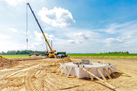 A construction site with a lifting crane and workers installing water pipesの写真素材