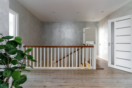 This hallway features a blend of modern design and natural elements with its wooden floor, white doors, and soft grey walls.の写真素材