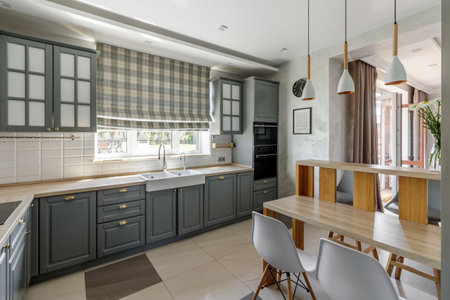 The spacious kitchen features grey cabinets, wooden countertops, and a cozy dining area bathed in natural light.の写真素材