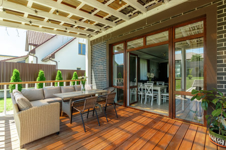 This image depicts a cozy outdoor patio area with comfortable seating, a table, and decorative plants, perfect for relaxation and gatheringsの写真素材