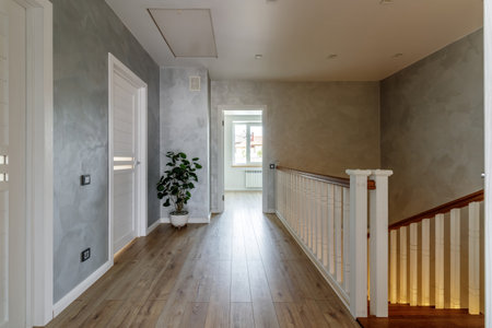 This hallway features a blend of modern design and natural elements with its wooden floor, white doors, and soft grey walls.の写真素材