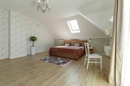 A comfortable attic bedroom with modern furnishings and natural light from a skylightの写真素材