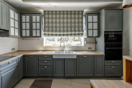 The spacious kitchen features grey cabinets, wooden countertops, and a cozy dining area bathed in natural light.の写真素材