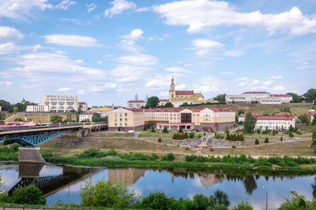 Scenic panoramic view of Grodno city with the Neman River, bridge, and historic architecture under a bright blue sky with clouds.の写真素材