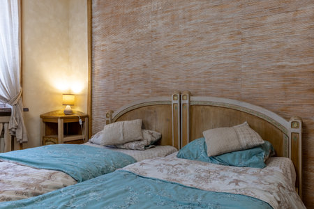 Close-up of a charming rustic bedroom featuring twin wooden beds with blue floral linens, textured...